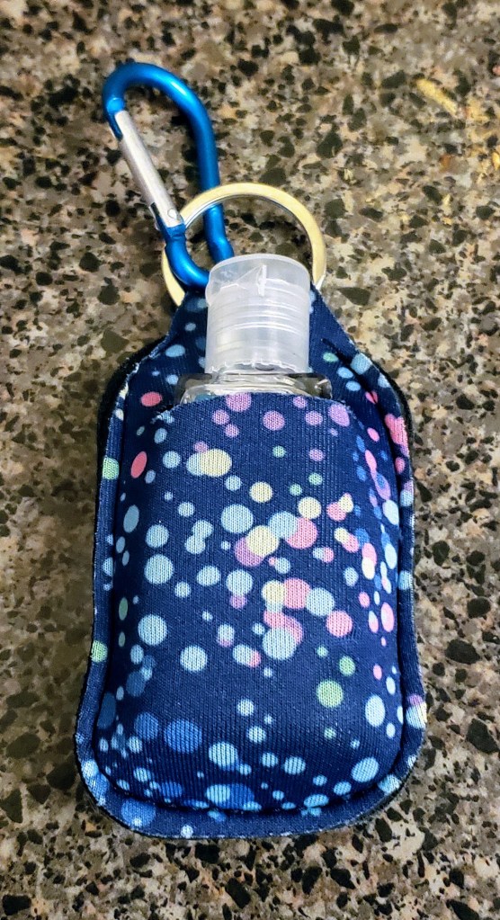 A keychain neoprene container with a little bottle of hand sanitizer