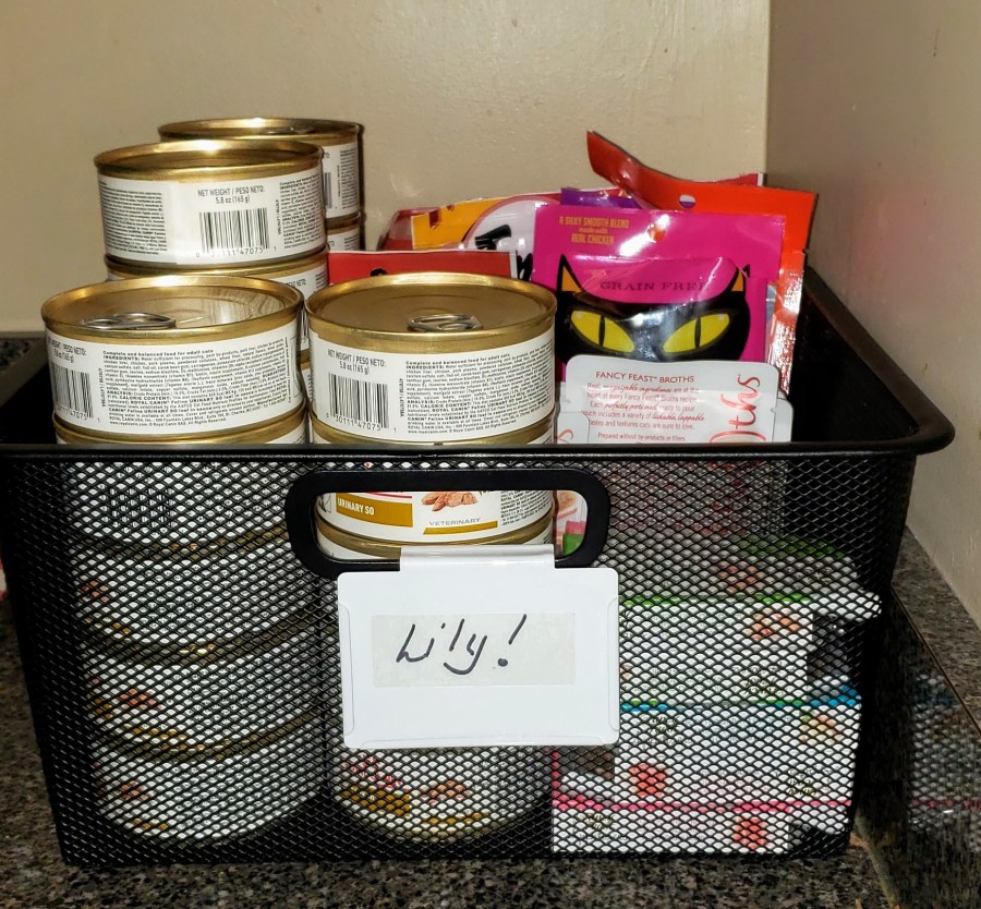 A black metal basket with cat food and treats
