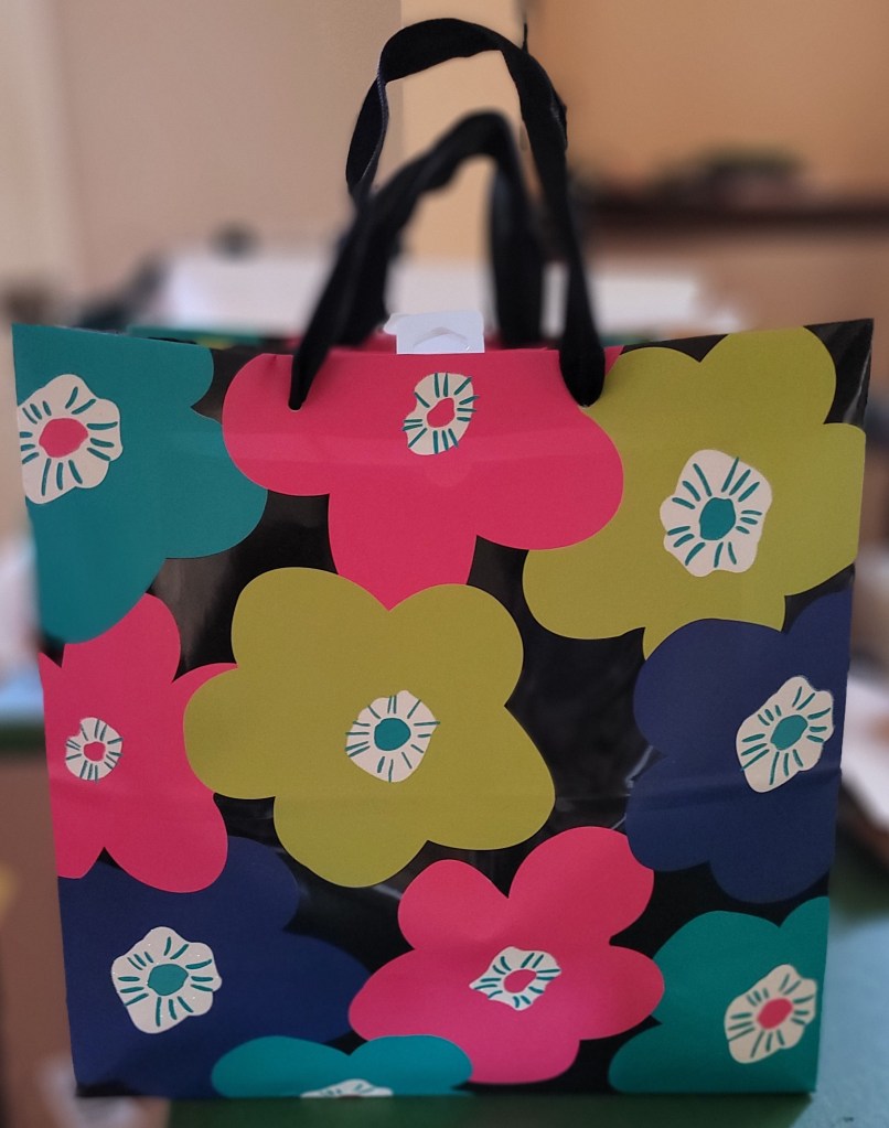 A gift bag with flowers on it with candy inside