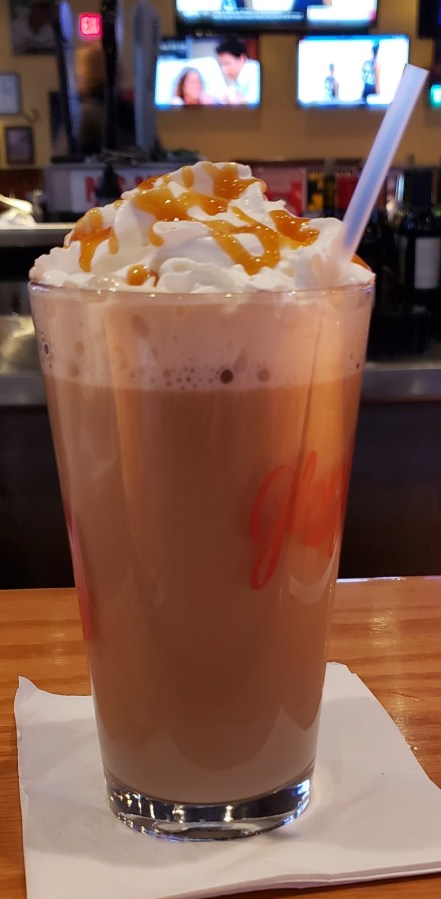A double Irish Coffee in a pint glass with whipped cream and caramel drizzle