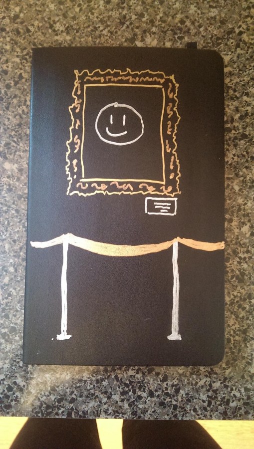 A black notebook with a framed smiley face with velvet ropes drawn on it from my museum studies class