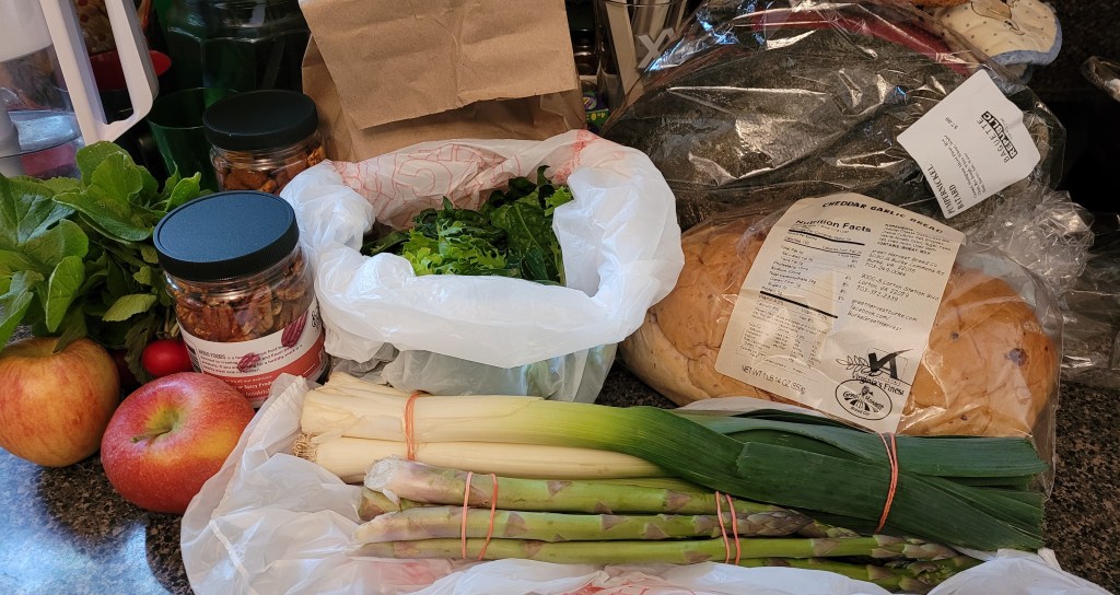Counter filled with bread and veggies and fruits from the farmers market