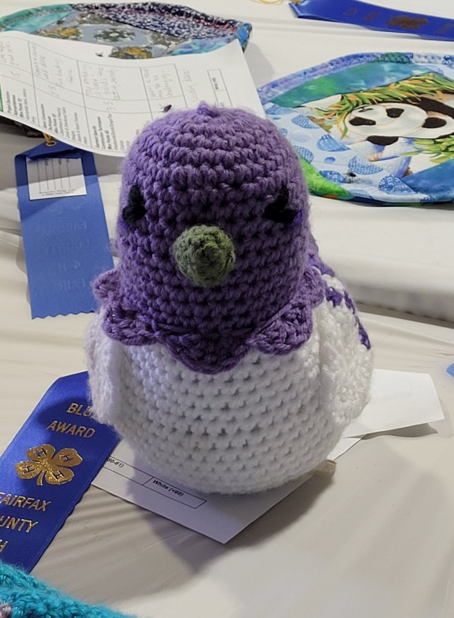 A prize winning crochet entry of a purple and white bird