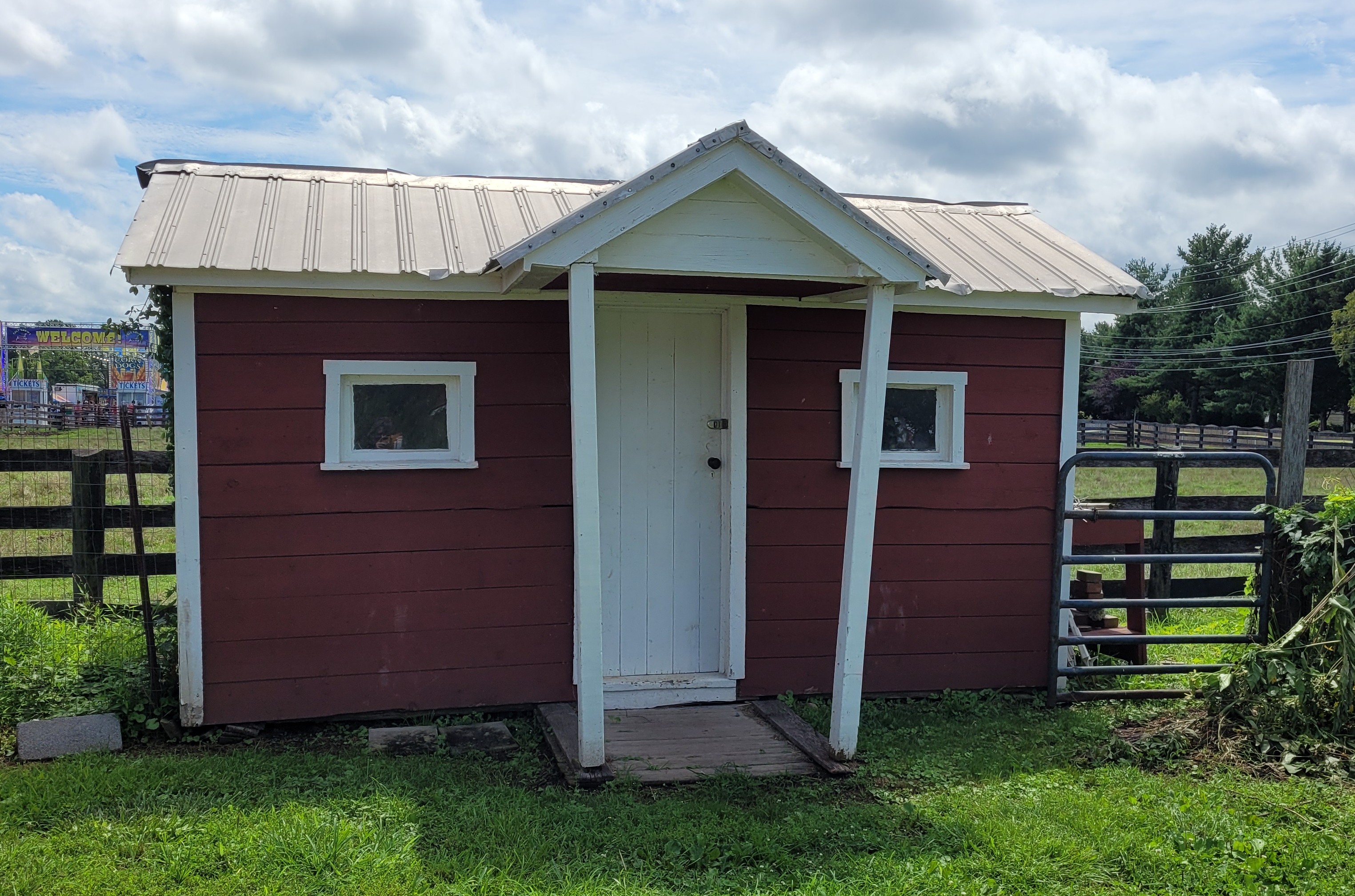 A small red building with a metal roof, and two tiny windows on either side of the front door
