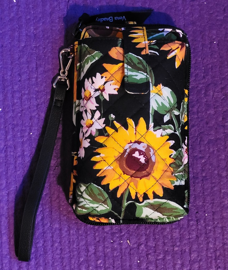 A black wristlet wallet with yellow sunflowers on it