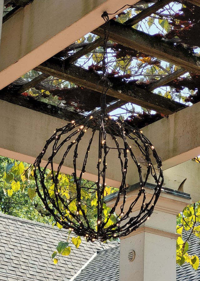A globe shaped light fixture made of bent sticks with twinkle lights
