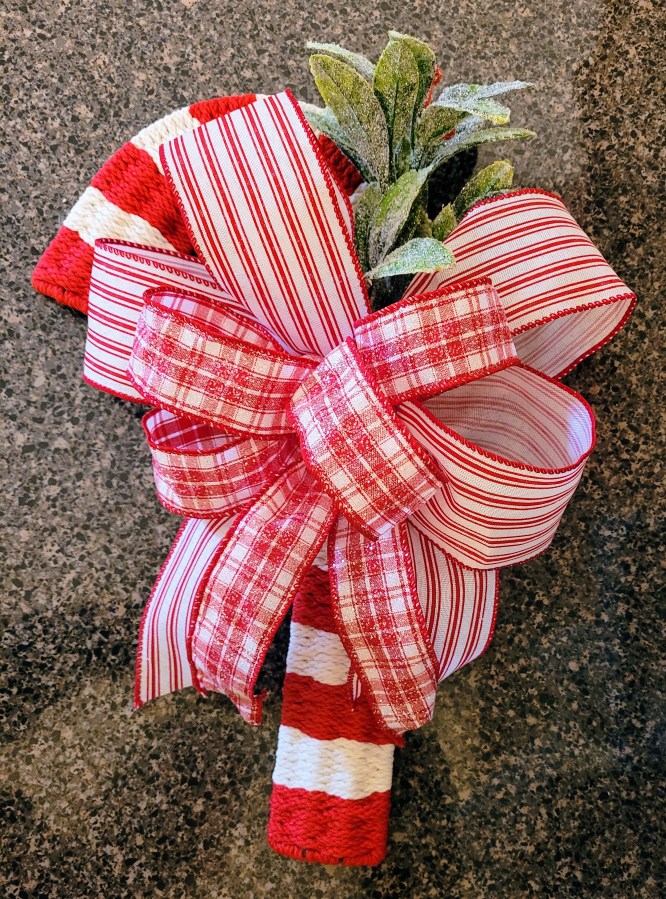 Candy Cane decoration with red and white ribbons and green frosted leaves