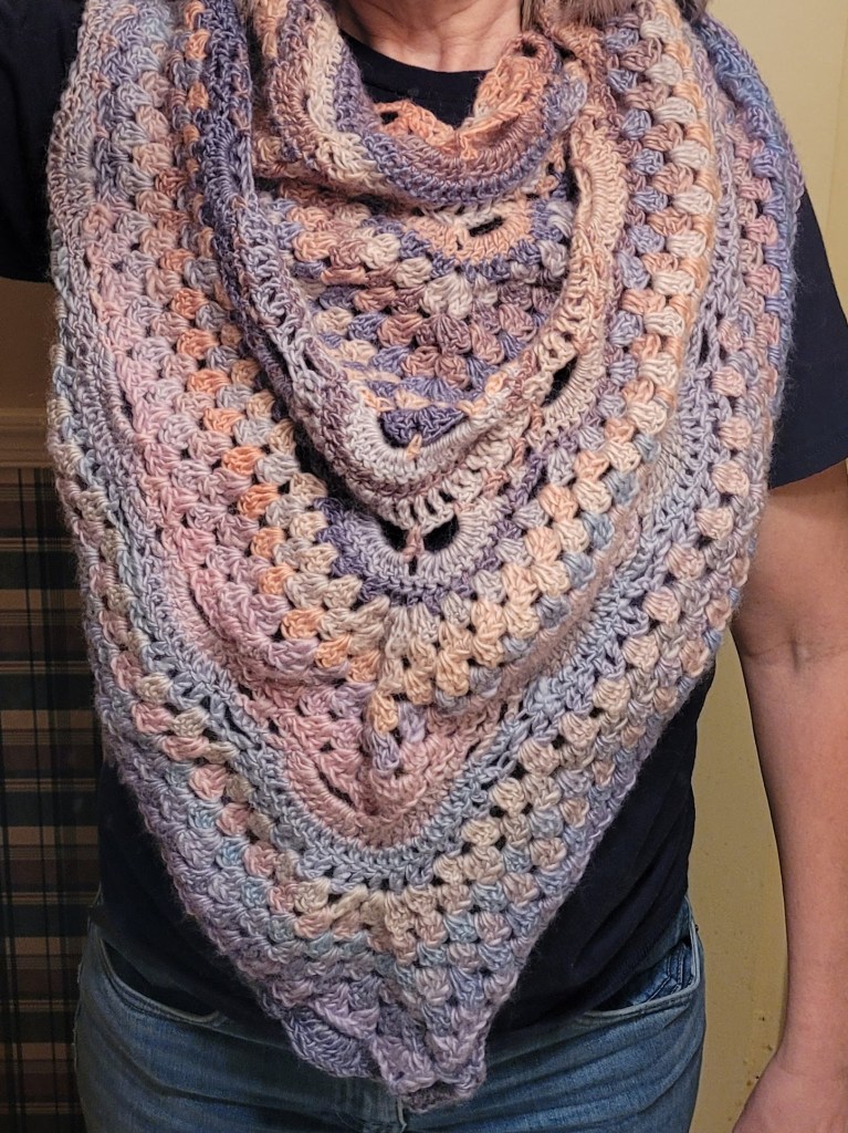 Crocheted wrap of muted pastels giving it an antique look.