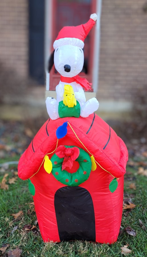 Inflatable decoration - Snoopy with a Santa hat on, sitting on a decorated doghouse, with Woodstock sitting on a present on his lap