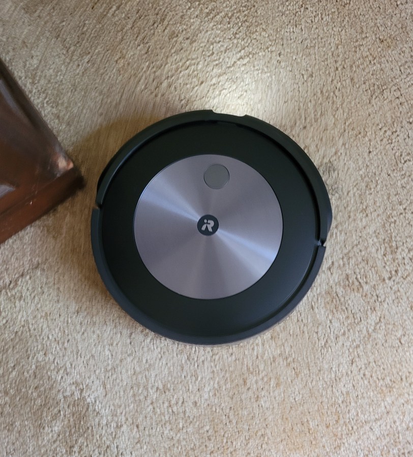 A Roomba on a beige carpet
