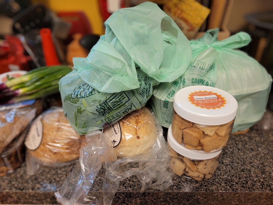 Shot of my farmers market haul - breads, shortbreads, spiced nuts, lettuces, green onions, and two containers of Jamaican jerk pork
