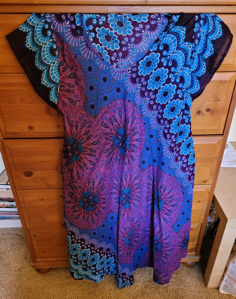 A short sleeved unstructured sundress with blue and purple flower patterns.