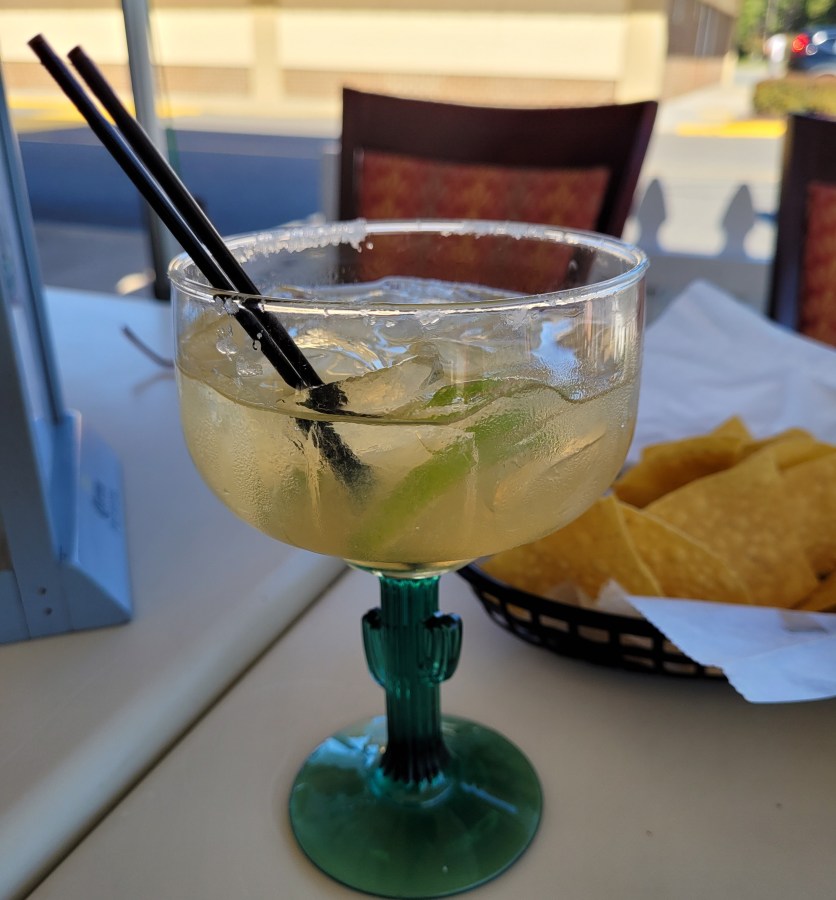 A traditional margarita on the rocks with salt, in a glass with a stem shaped like a cactus!