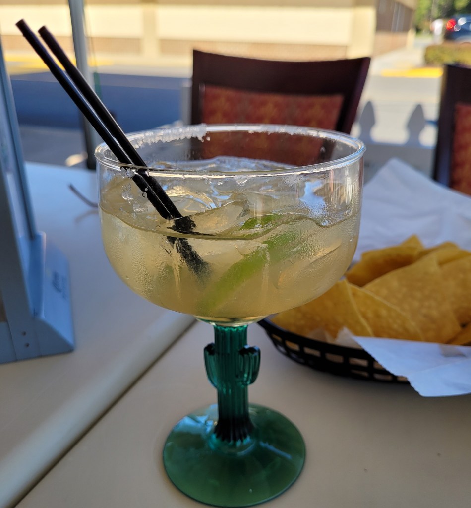 A traditional margarita on the rocks with salt, in a glass with a stem shaped like a cactus!